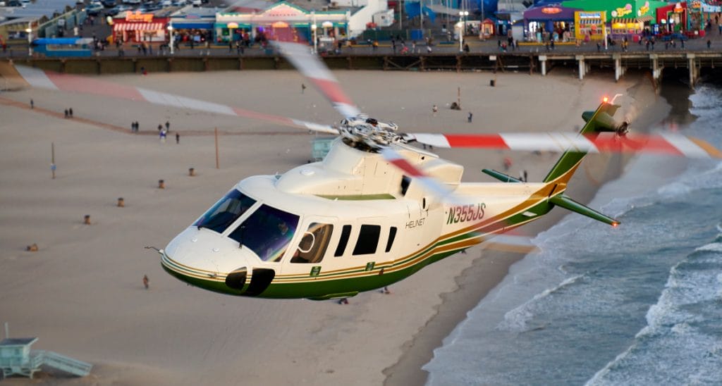 Airbus AS350 helicopter flying over a beach