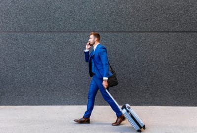 Handsome young man on business trip walking with his luggage.